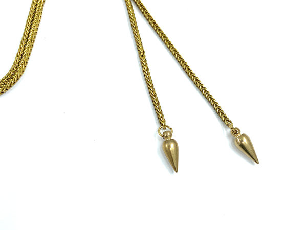 Close-up of brass spike bolo tie tips on a white background