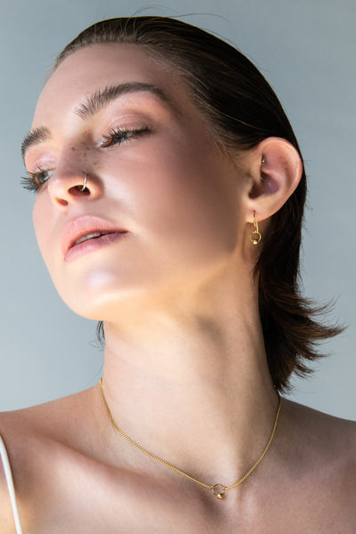 Close-up of model wearing gold choker and matching earrings