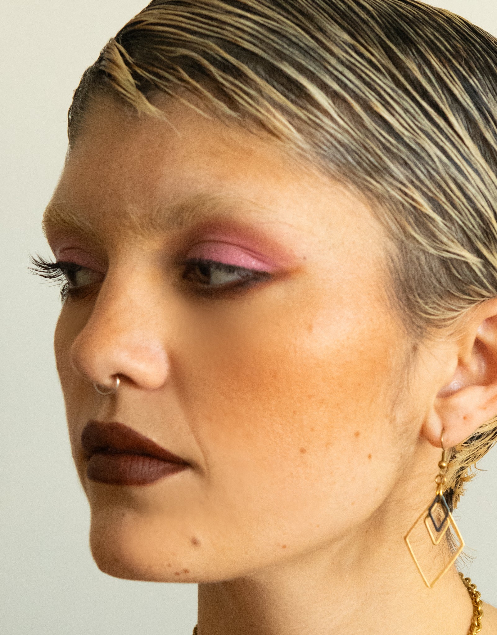 Side view of model wearing black and gold triple diamond charm earrings