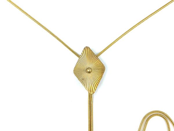 Close-up of gold diamond pendant of bolo tie on a white background