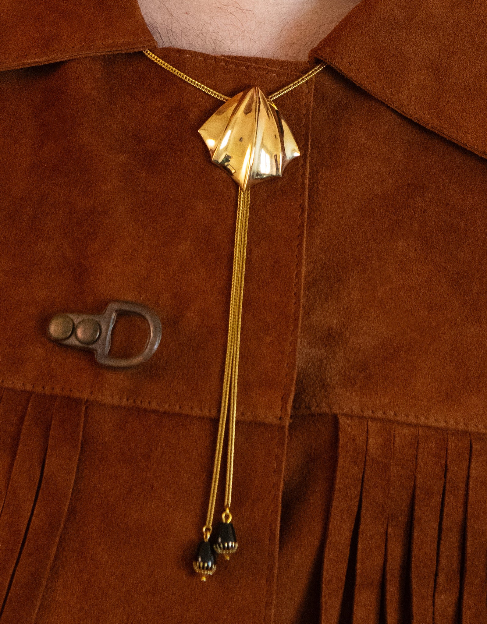 Close-up of model wearing gold fin bolo tie and tan fringe jacket