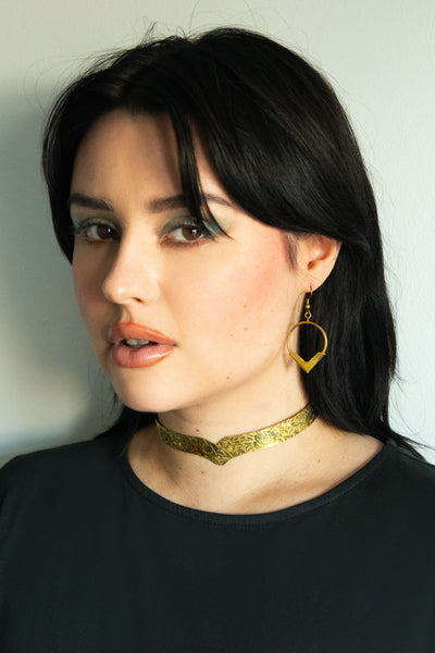 Model wearing gold flower choker and gold pointed hoop earrings