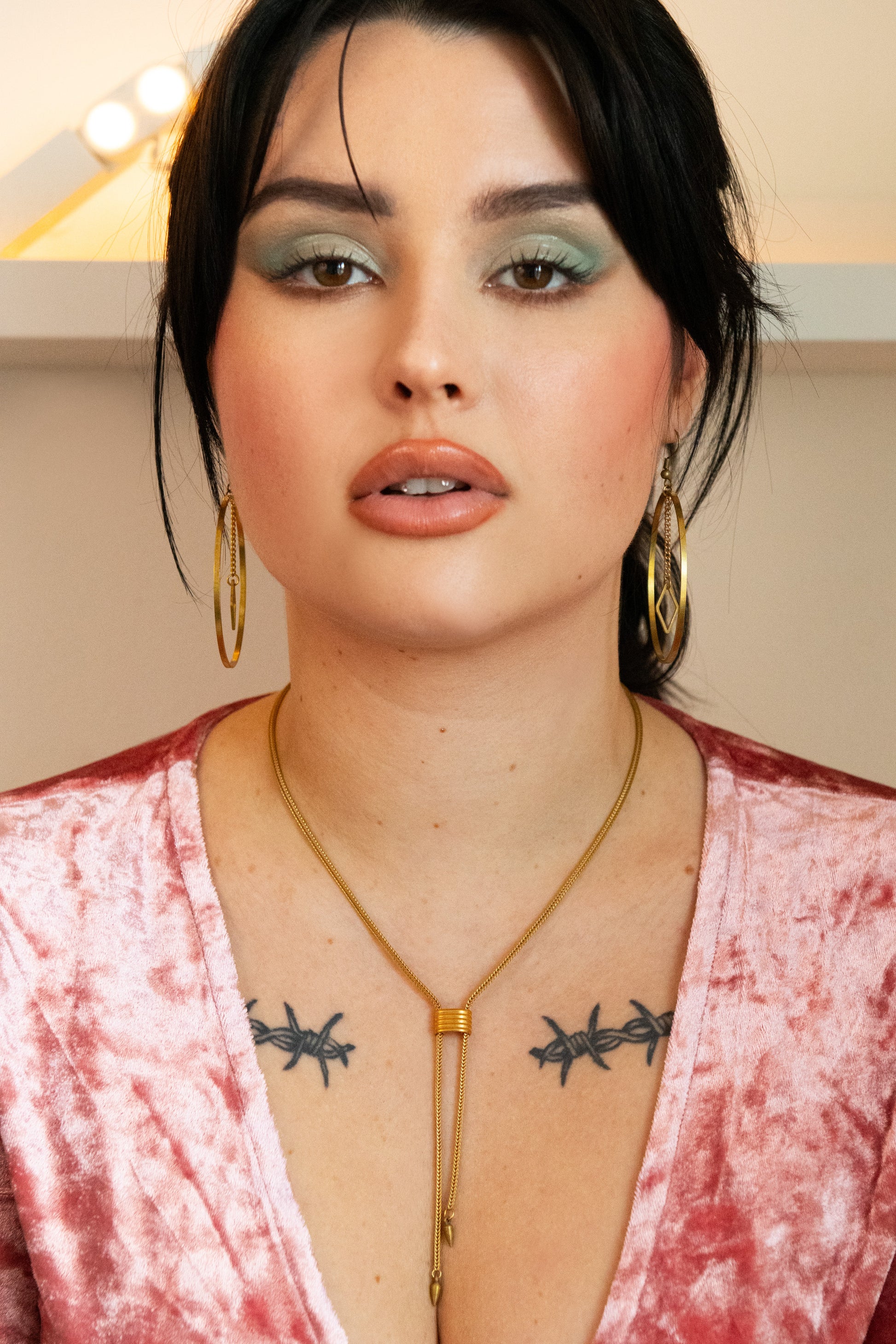 Front view of model wearing large gold hoop earrings and adjustable gold choker necklace