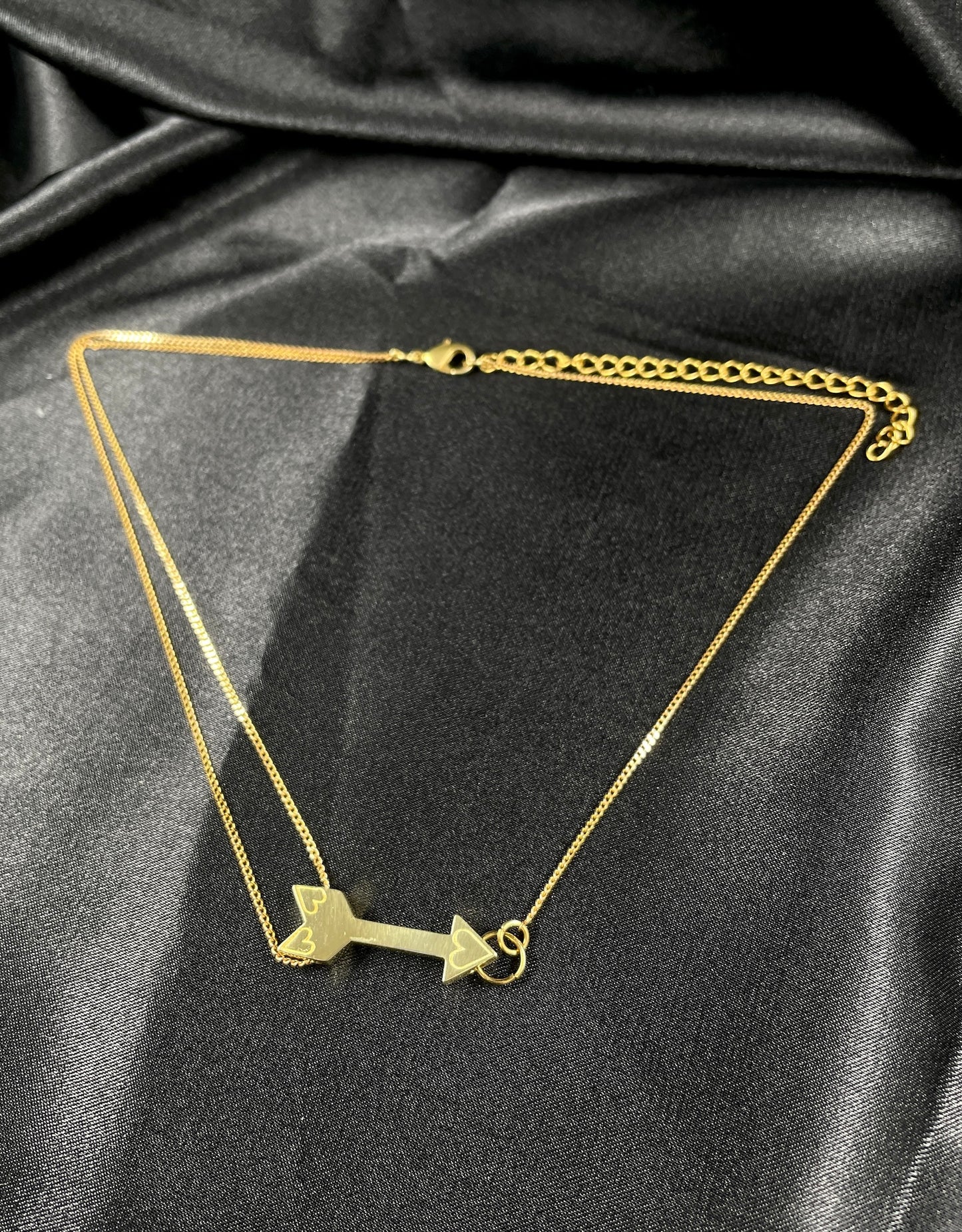 Gold arrow choker on a black silk background