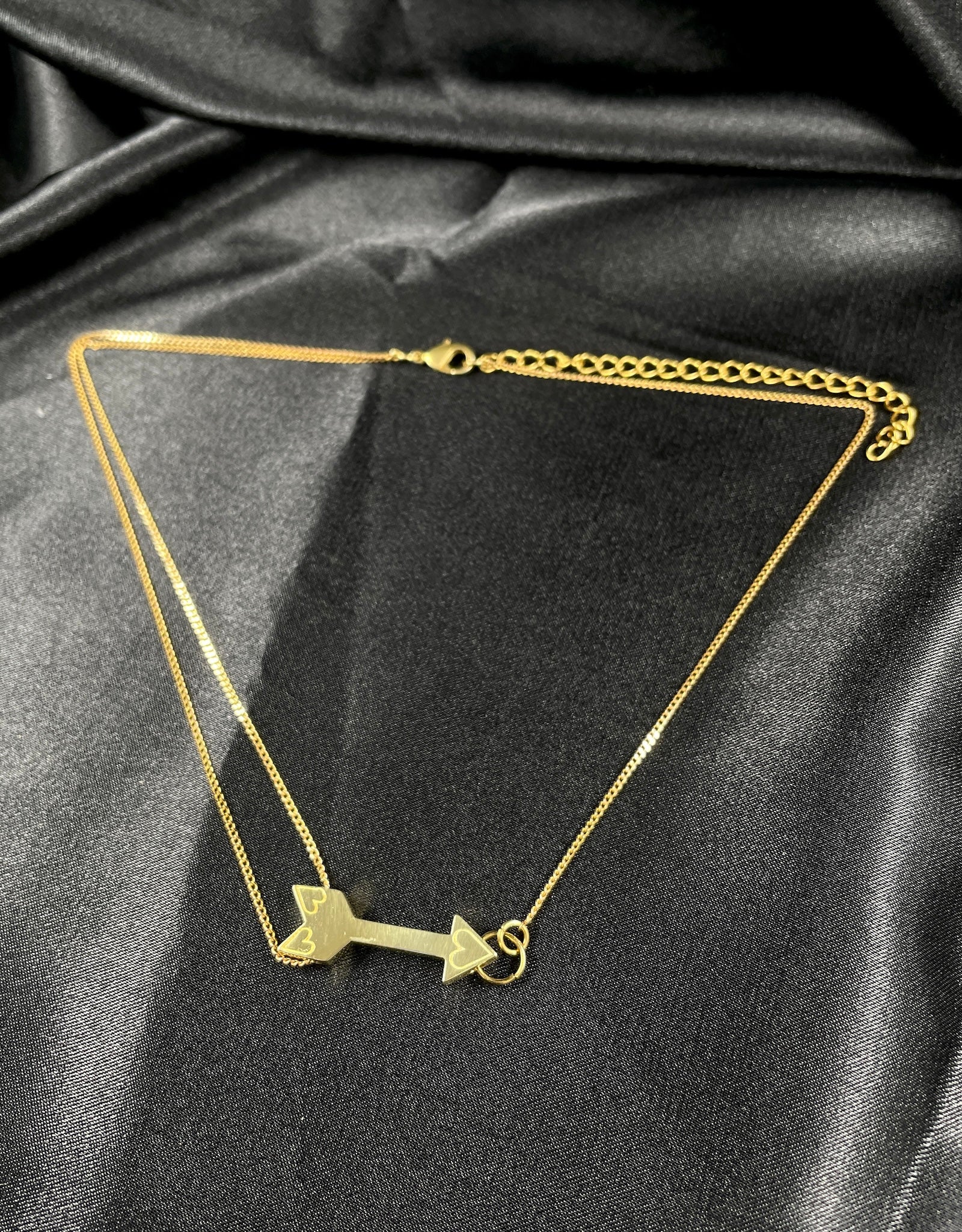 Gold arrow choker on a black silk background