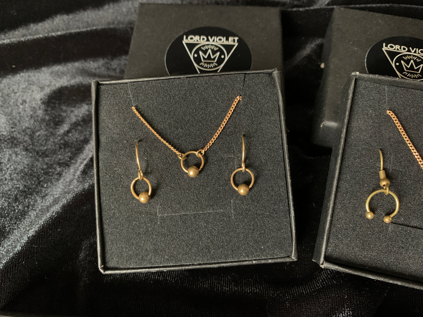 Captive barbell choker and earrings in a black gift box on a black velvet background