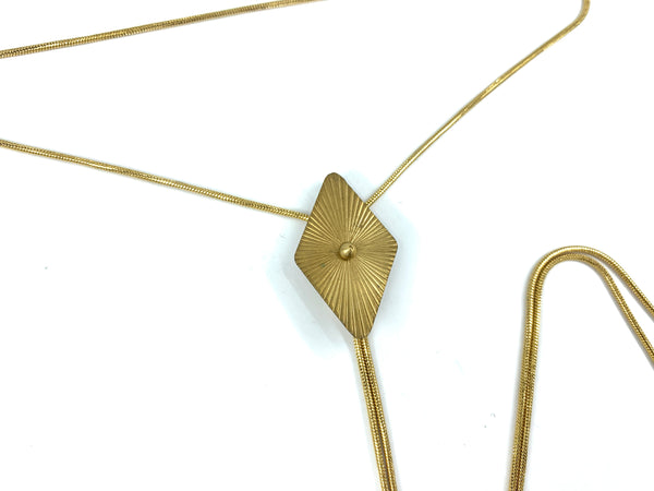 Close-up of gold ridged diamond bolo tie pendant on a white background
