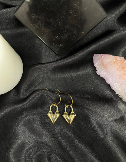 Heart locket charm earrings on a black silk background