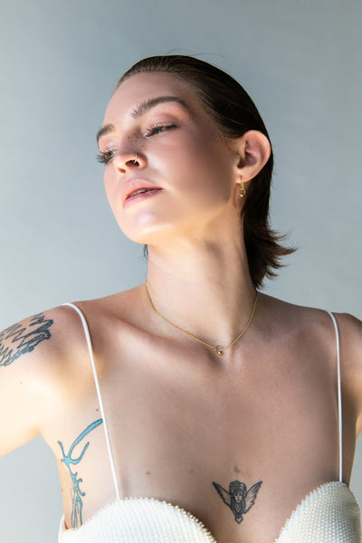 Model wearing delicate gold captive barbell choker and earrings