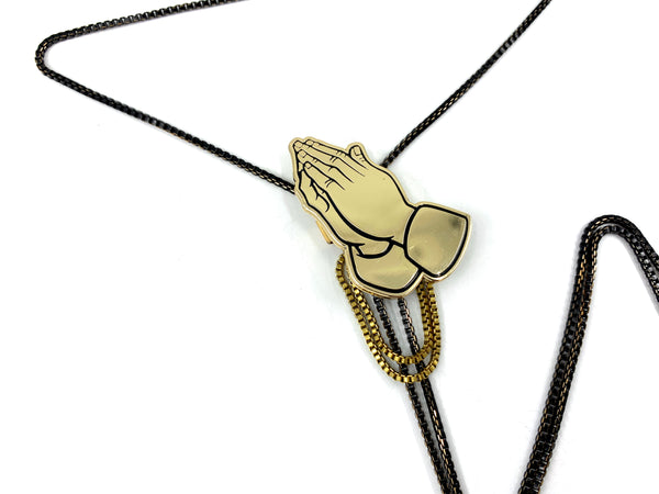 Close-up of praying hands pendant of bolo tie on a white background