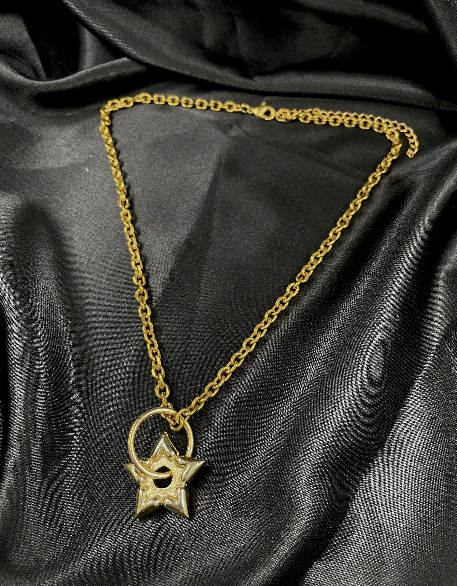 Gold heart spur choker necklace on a black silk background