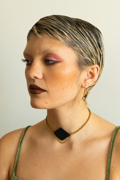 Model wearing leather choker necklace and triangle charm earrings