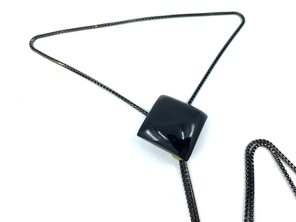 Close-up of onyx pendant of bolo tie on a white background