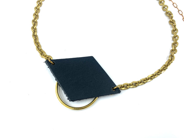 Close-up of a leather pendant with o-ring  of handmade choker necklace on a white background