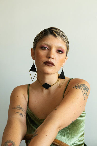 Model wearing matching leather choker and earrings and a green velvet dress