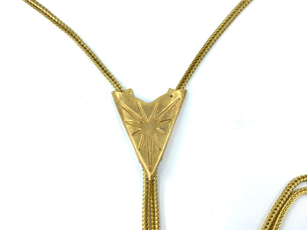 Close-up of gold star pendant of bolo tie necklace on a white background