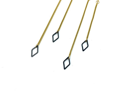 Close-up of black diamond charms and foxtail snake chain of dangle earrings on a white background