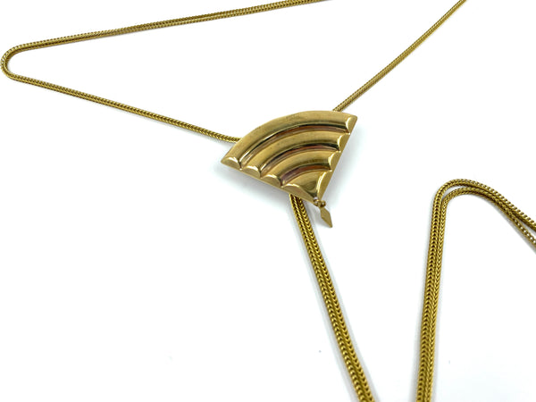 Close-up of gold fan pendant of bolo tie on a white bakground