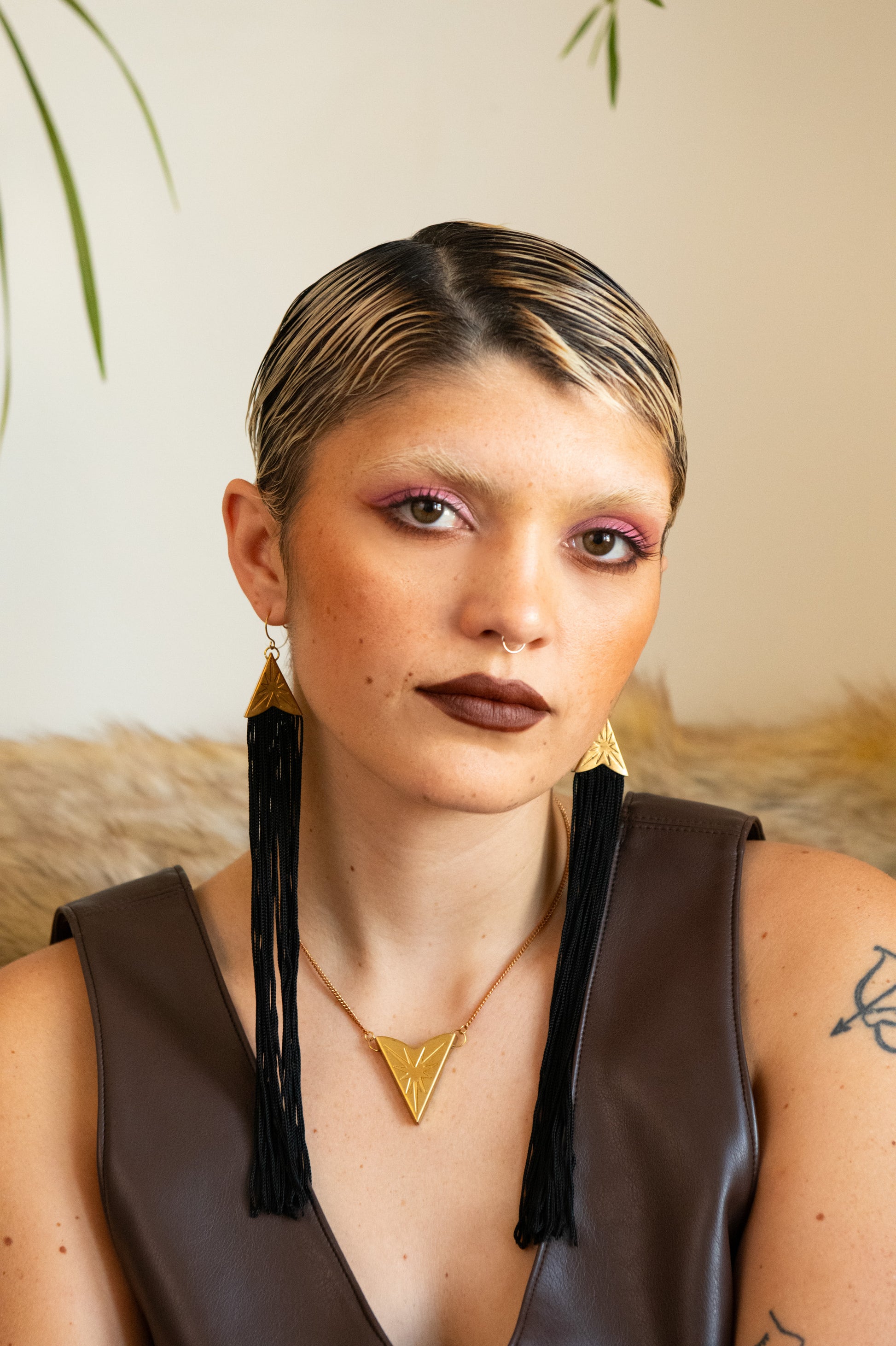 Model wearing star choker necklace, matching star tassel earrings and a beige pleather dress