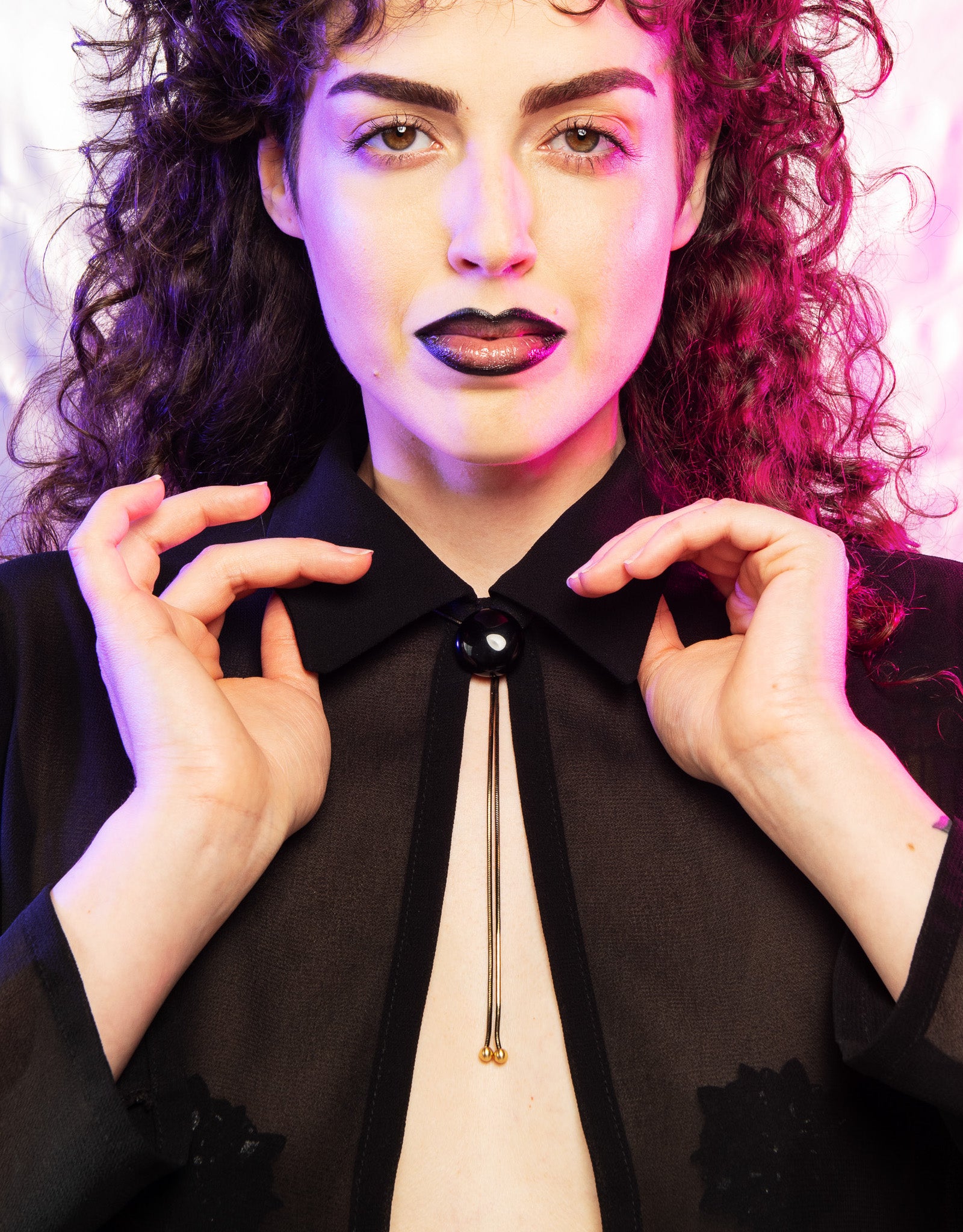 Model wearing onyx bolo tie and translucent black collared top