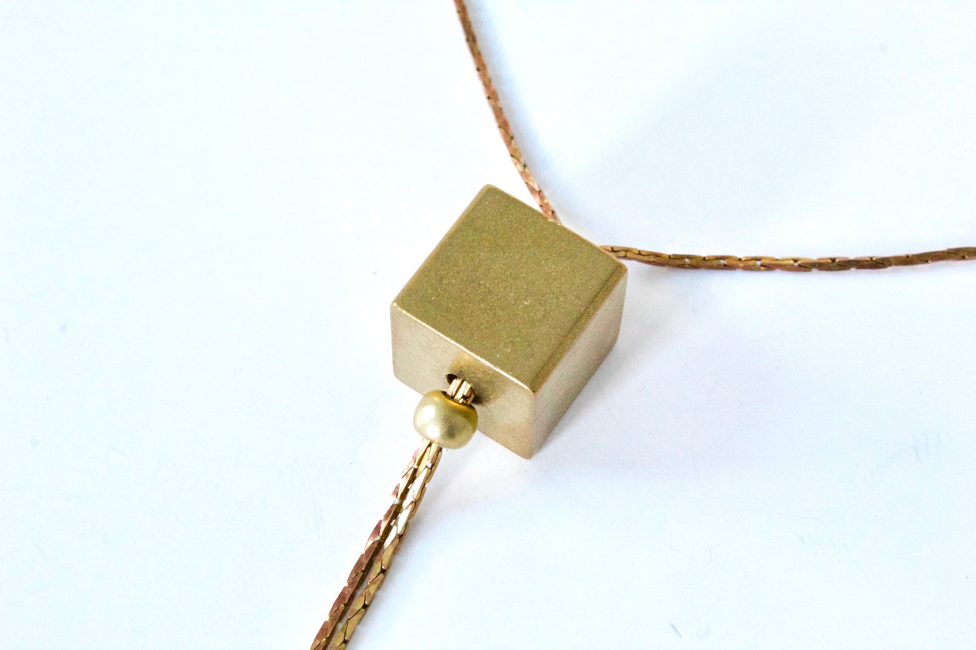 Close view of gold cube necklace pendant.