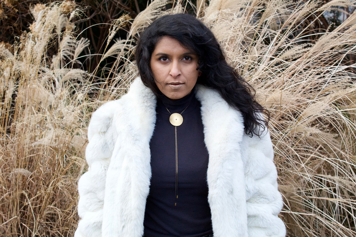 Model wearing faux fur coat and large bolo tie necklace