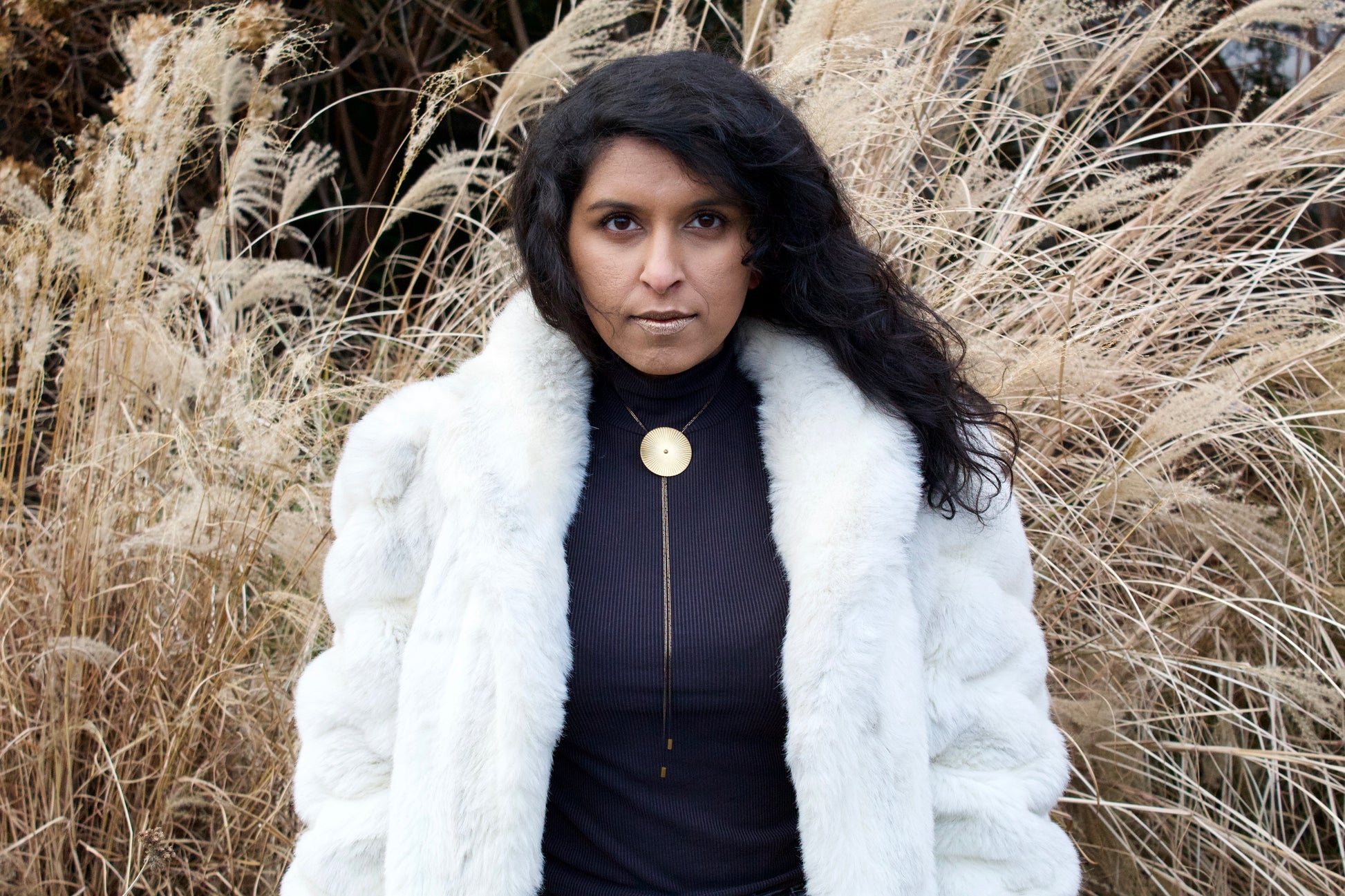 Model wearing faux fur coat and large bolo tie necklace