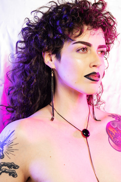 Side shot of model wearing onyx bolo tie and tassel earrings
