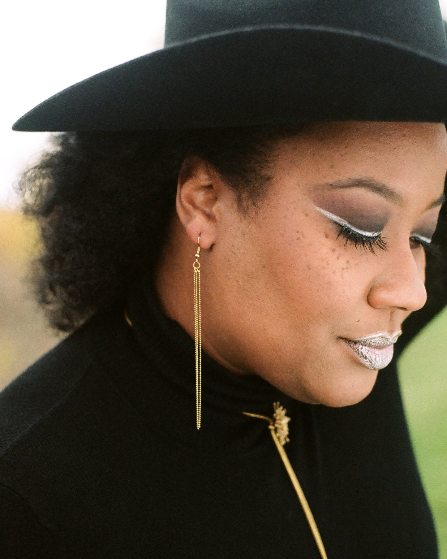 Side view of model wearing gold tassel earrings