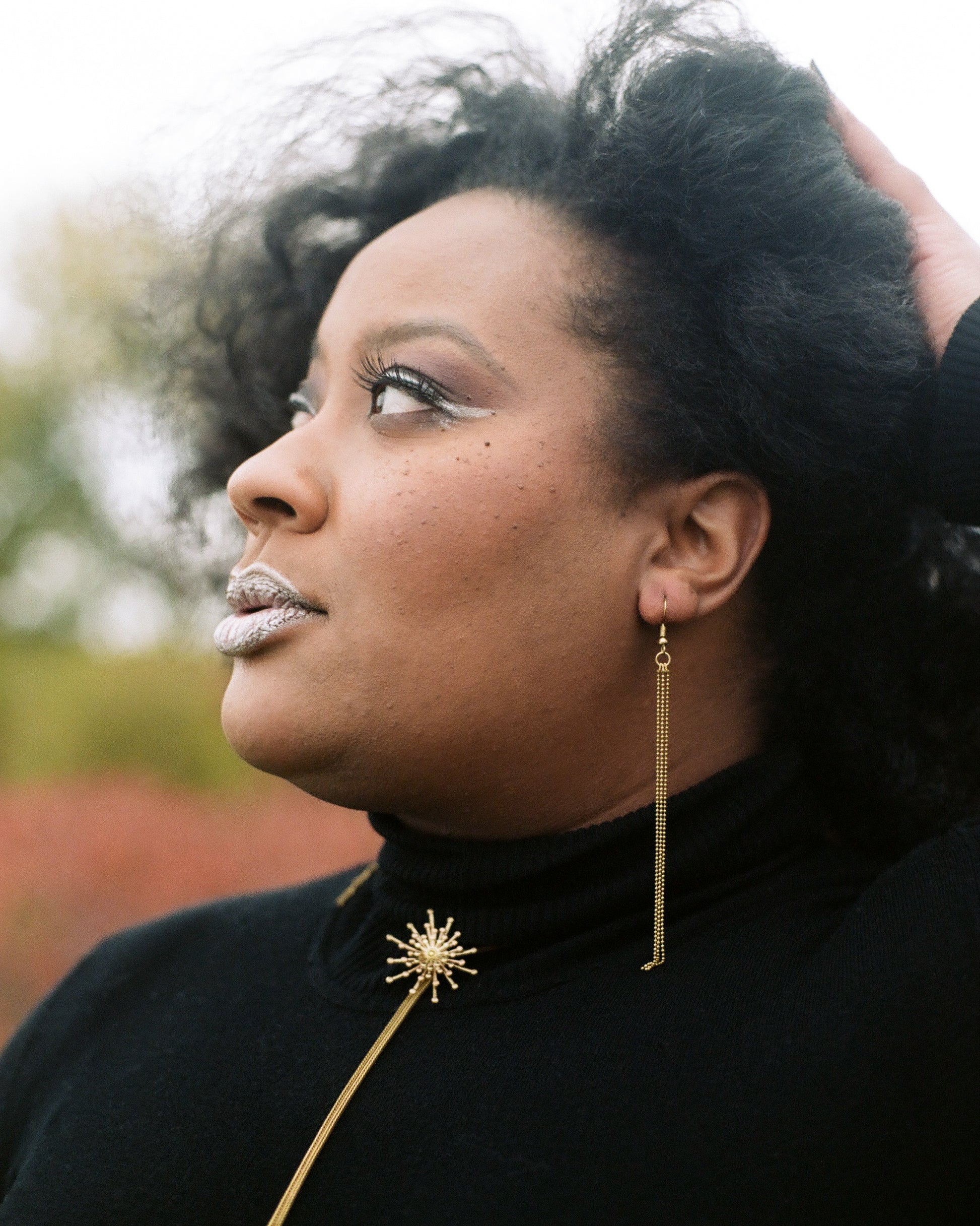 Model wearing gold ball chain tassel earrings and STARBURST Bolo Tie Necklace