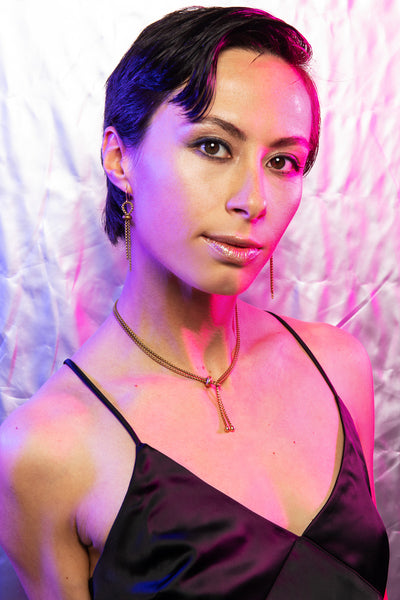 Model wearing lasso necklace, matching earrings and a black satin spaghetti strap dress
